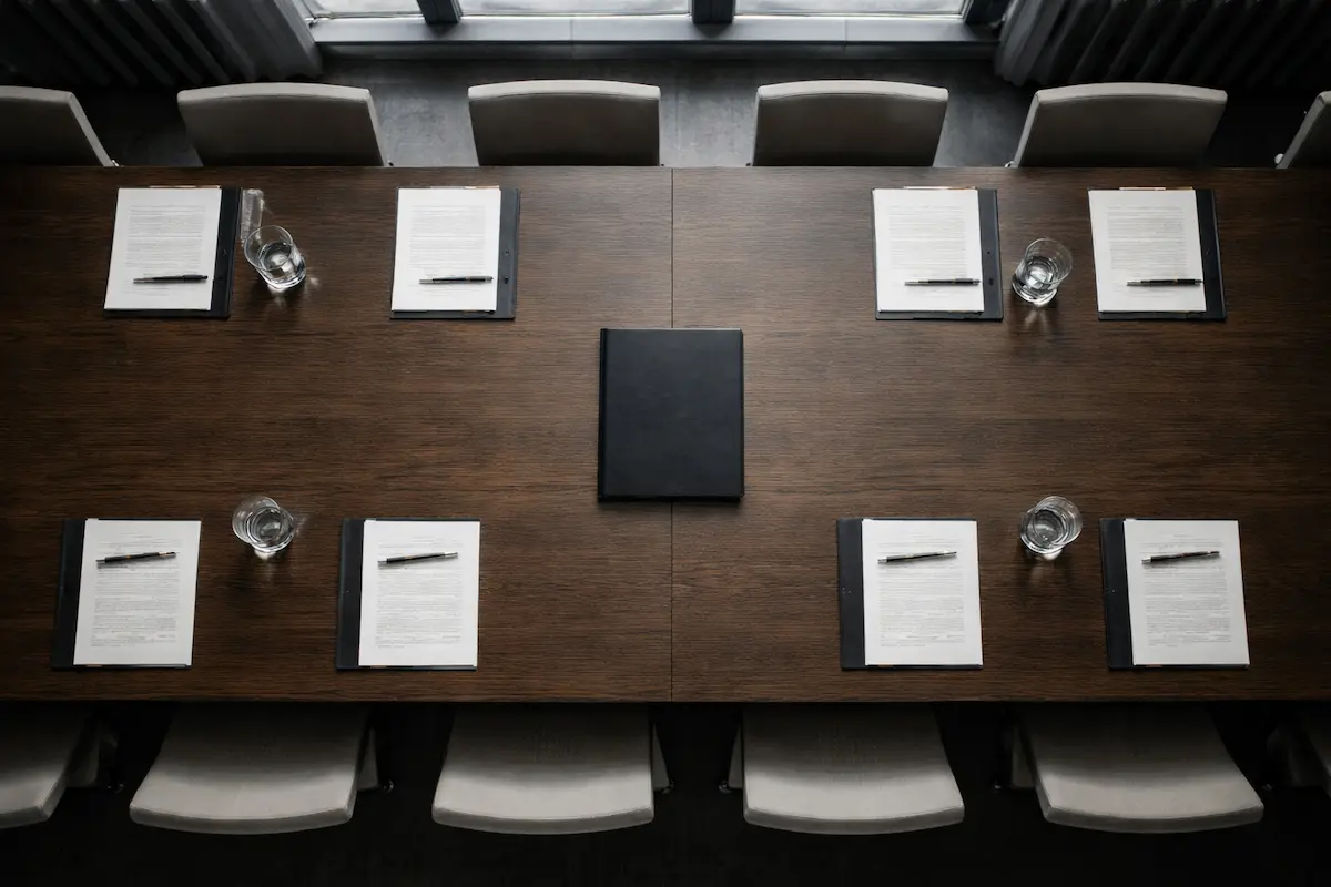Table de négociation structurée : dossiers, documents et verres d’eau disposés pour une réunion de décision